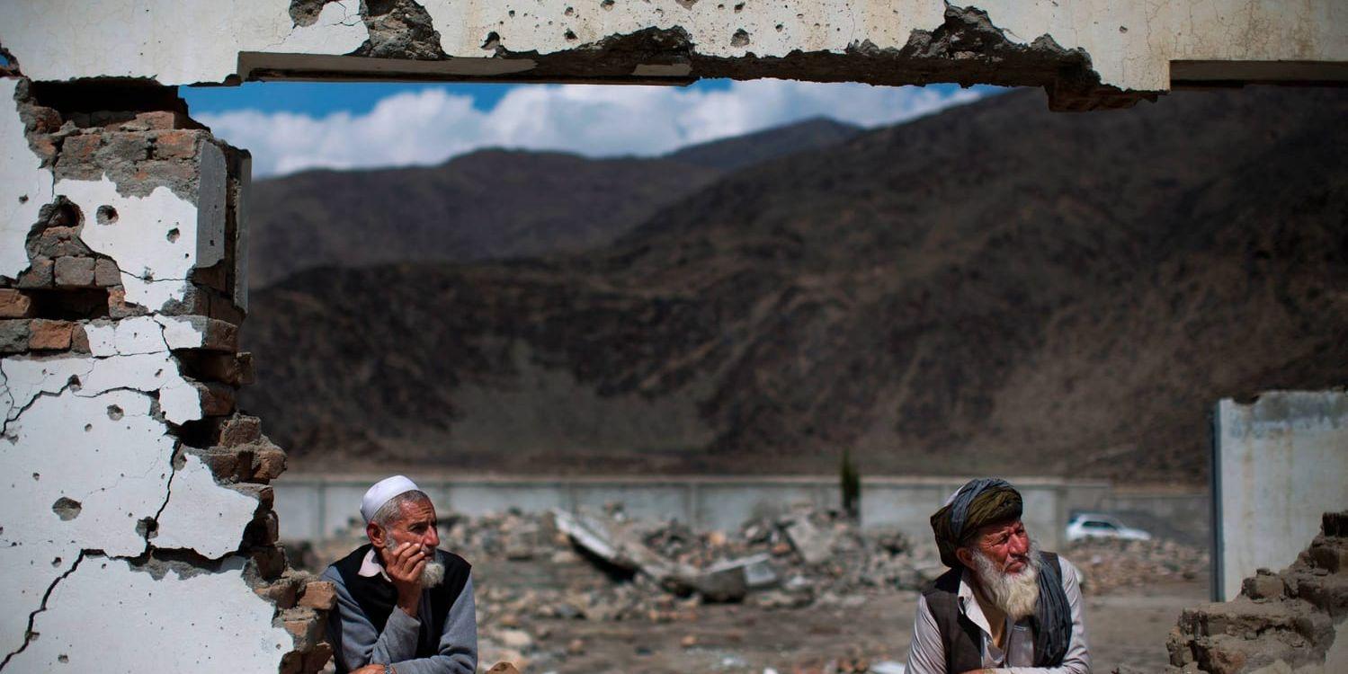Två afghanska män tittar genom fönstret på en förstörd byskola efter en attack av talibanrebeller. Arkivbild.