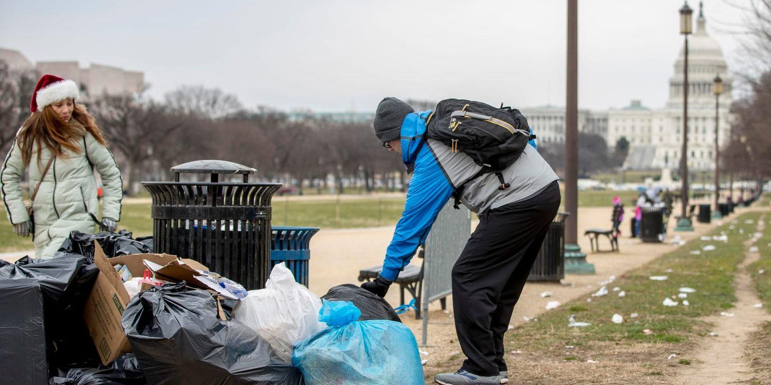 En frivilig tar hans om sopor vid grönområdet National Mall i USA:s huvudstad Washington DC. I bakgrunden syns kongressbyggnaden Capitolium, där en eventuell budgetuppgörelse om att öppna statsapparaten måste godkännas.