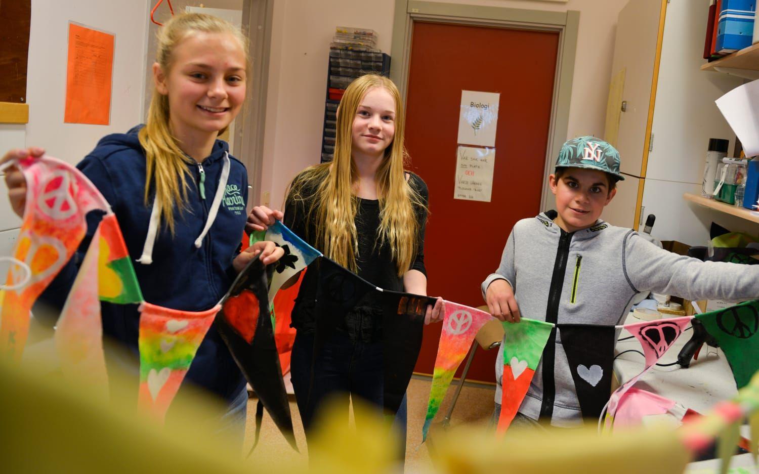 Långt kärleksbudskap. Maja Blom, Ebba Karlsson och Isaac Johansson hjälpte till att sätta fast flaggorna, som de och klasskompisarna skapat, på ett långt snöre. Bild: Kristina Stulken