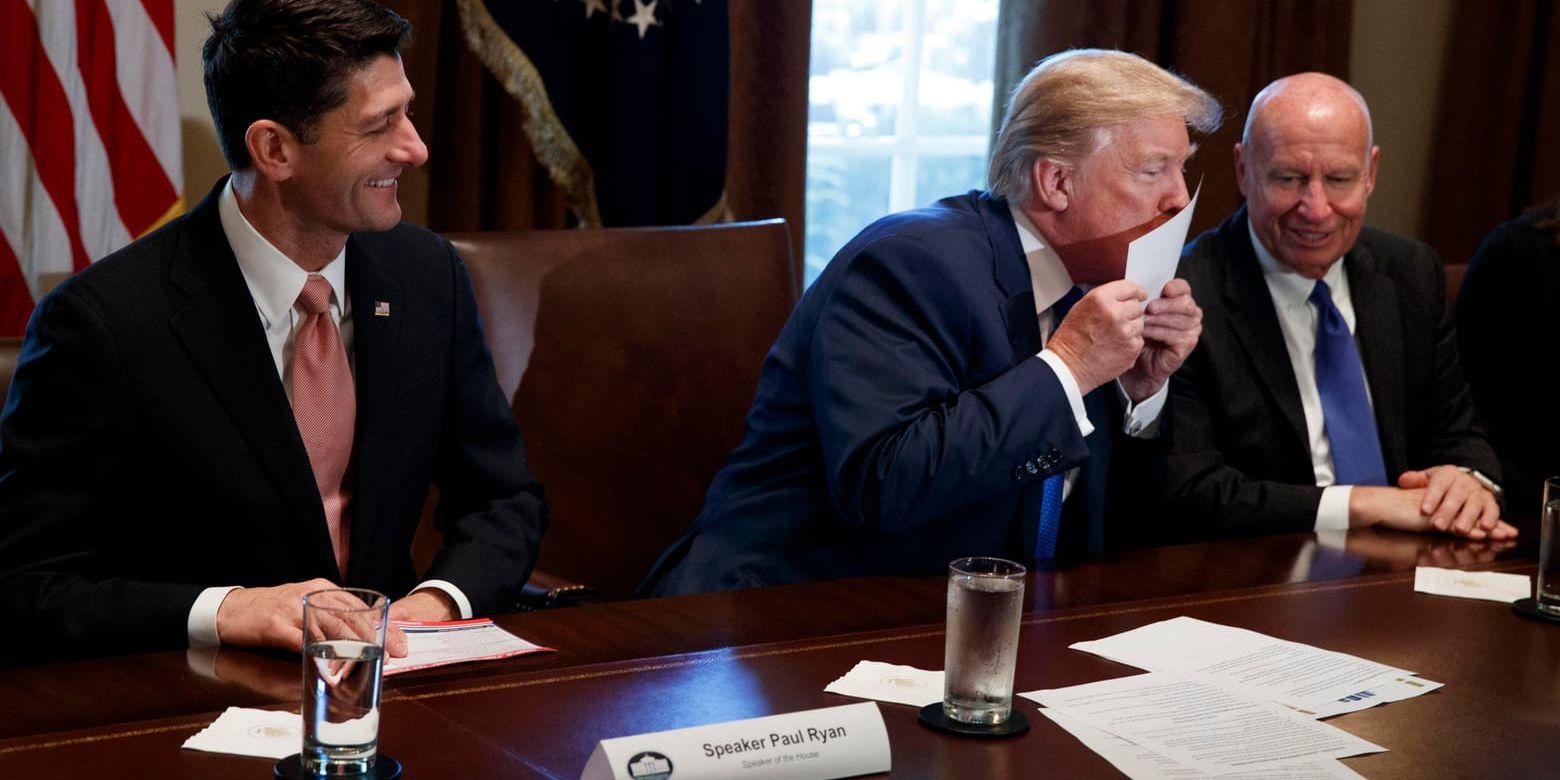 USA:s president Donald Trump kysser en utskrift av det som kan komma att bli landets nya skattereform under ett möte i Vita huset. Till vänster om presidenten sitter talman Paul Ryan, till höger sitter ordföranden i representanthusets skatteutskott Kevin Brady.