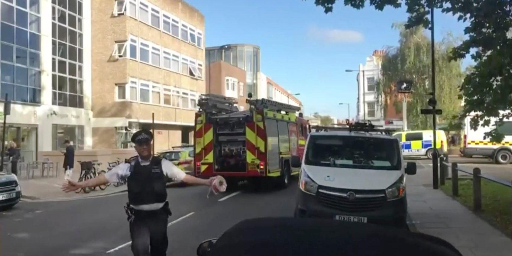 En polis stoppar förbipasserande vid Parsons Green i London.