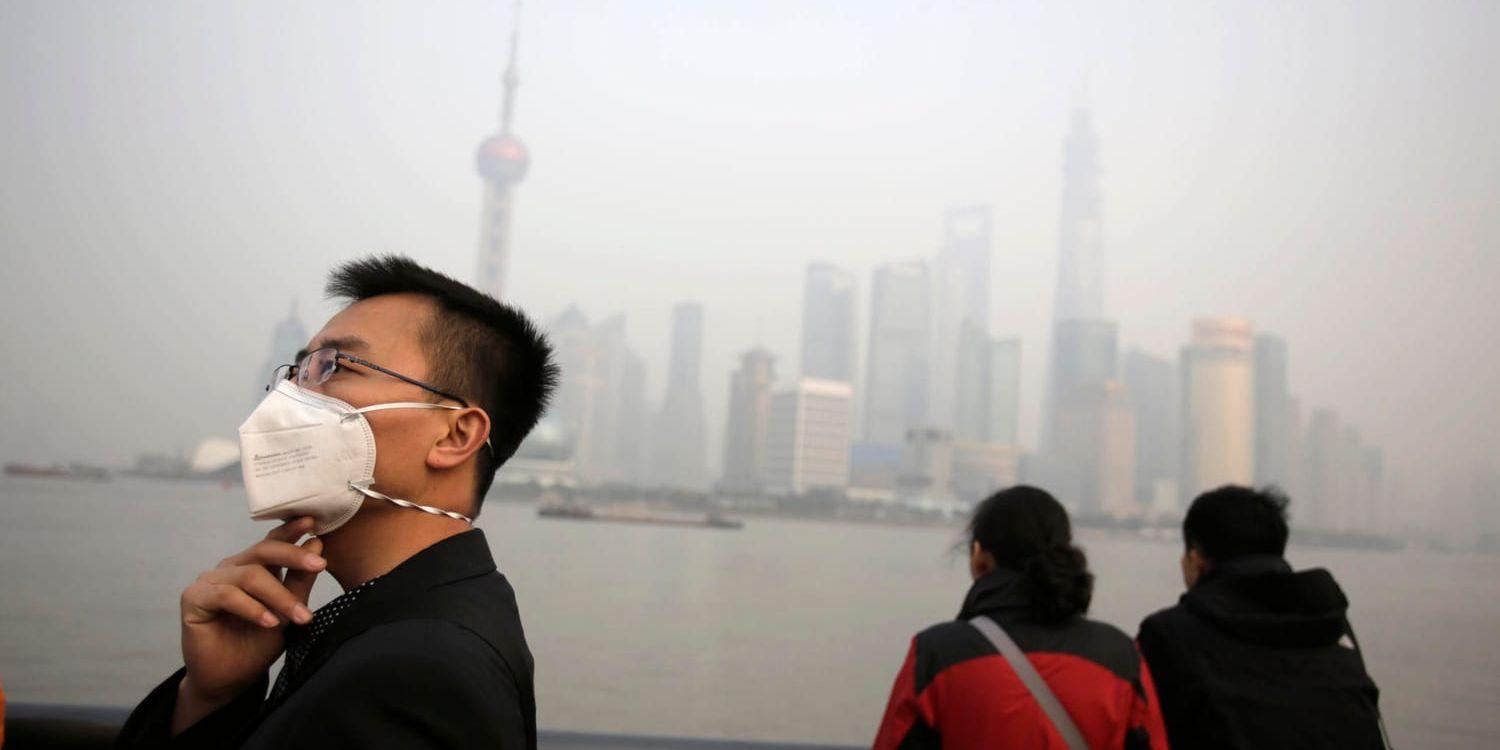 En man bär en andningsmask för att skydda sig mot den förorenade luften, vid Huangpufloden i Shanghai. Arkivbild.