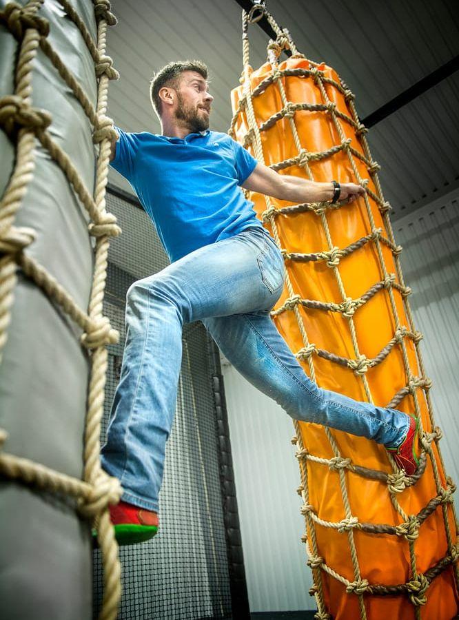Platsansvarige Fredrik Svensson visar sin skicklighet i att klättra. I en del av arenan har man byggt upp som en gladiatorbana, där man kan tävla mot kompisar. Men lika viktigt är att ha trevligt och umgås. Bild: Stefan Bennhage