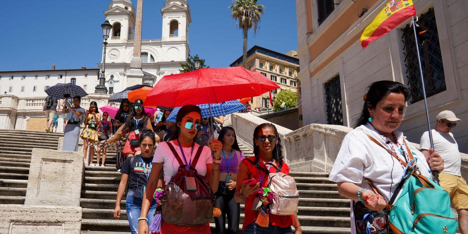 Turister skuggar sig med paraplyer när de går nerför Spanska trappan i Rom på tisdagen.