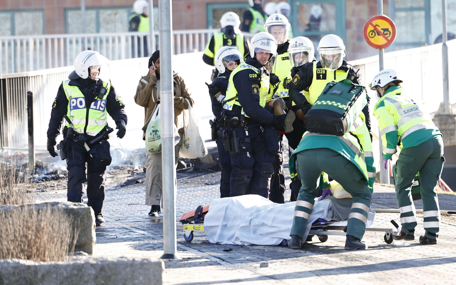 Polis och ambulanspersonal bär på en skadad man som skjutits i benet under upploppen i Navestad i Norrköping på påskdagen.Oroligheterna utlöstes av att den högerextrema provokatören Rasmus Paludan har sagt att han ska återvända till Östergötland för nya demonstrationer under dagen.