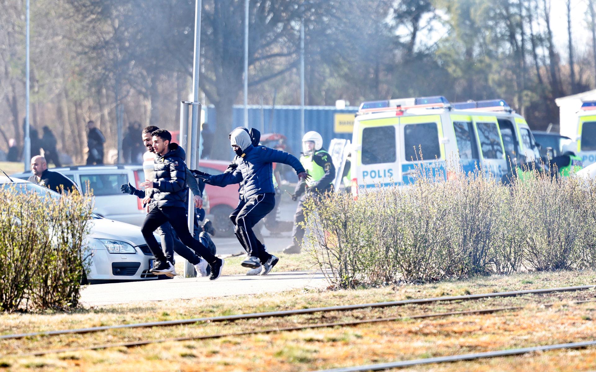 Personer springer från kravallutrustad polis i samband med upplopp i Navestad i Norrköping på påskdagen.Oroligheterna utlöstes av att den högerextrema provokatören Rasmus Paludan har sagt att han ska återvända till Östergötland för nya demonstrationer under dagen.