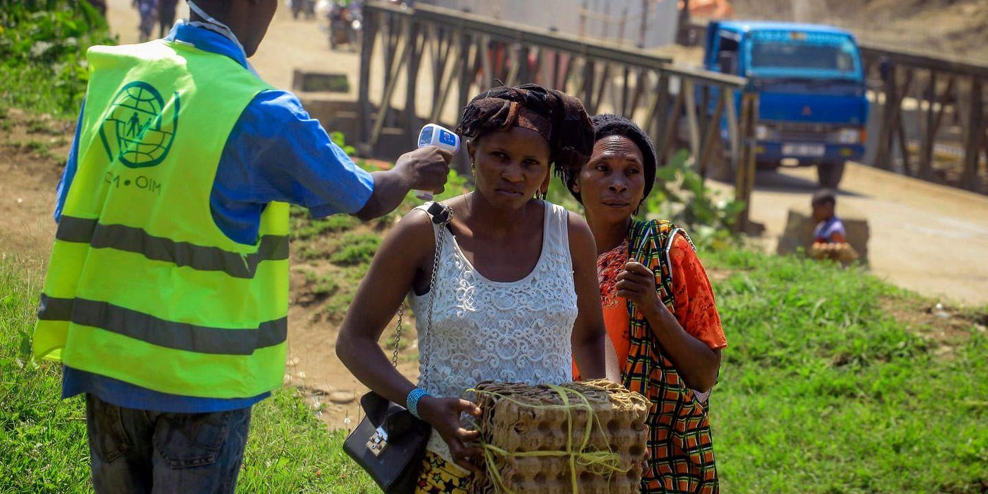 En man tar tempen på två kvinnor som korsar gränsen mellan Kongo-Kinshasa och Uganda den 12 juni 2019.