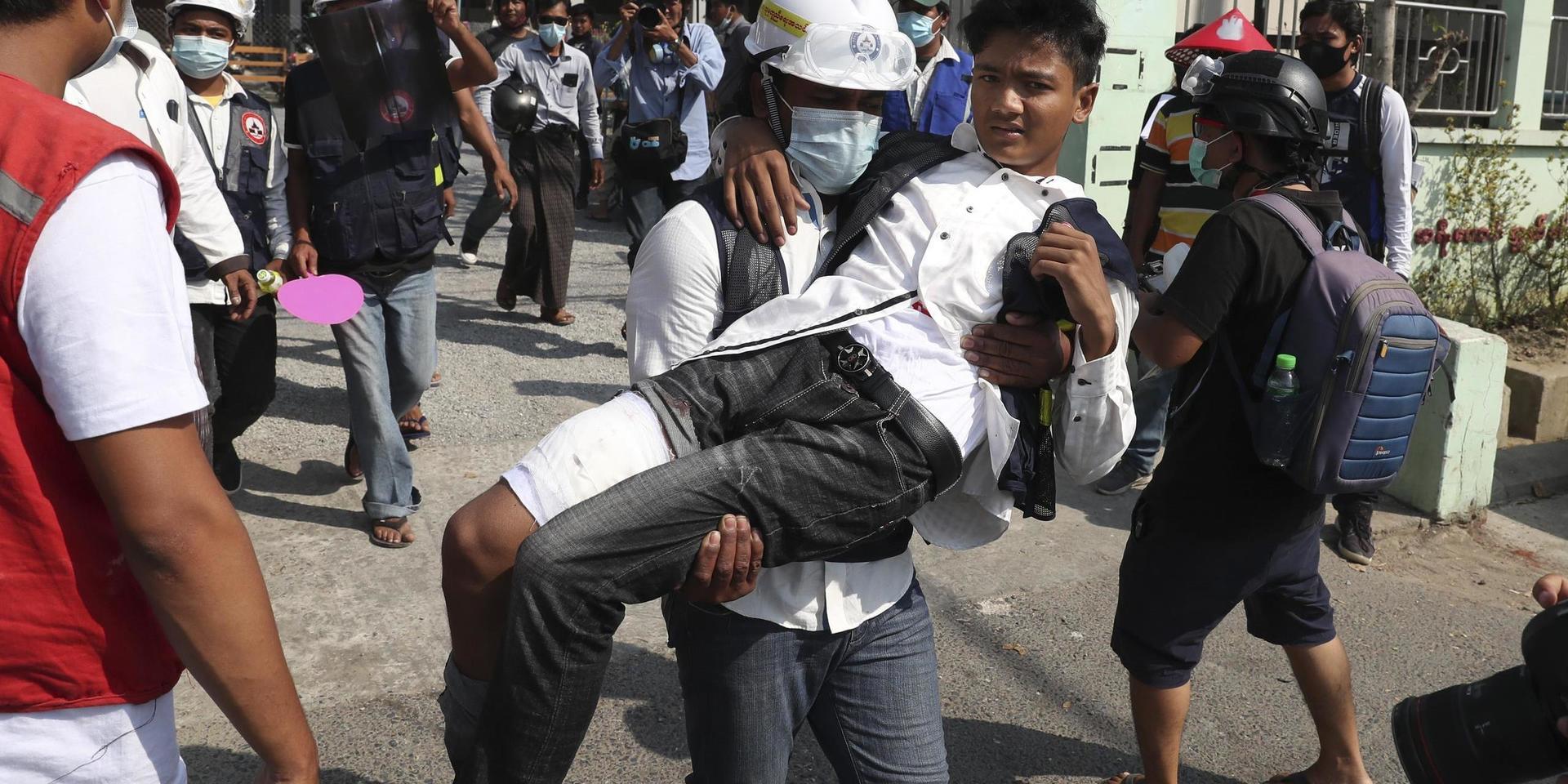 En skadad demonstrant bärs i väg av en meddemonstrant i Mandalay på söndagen.
