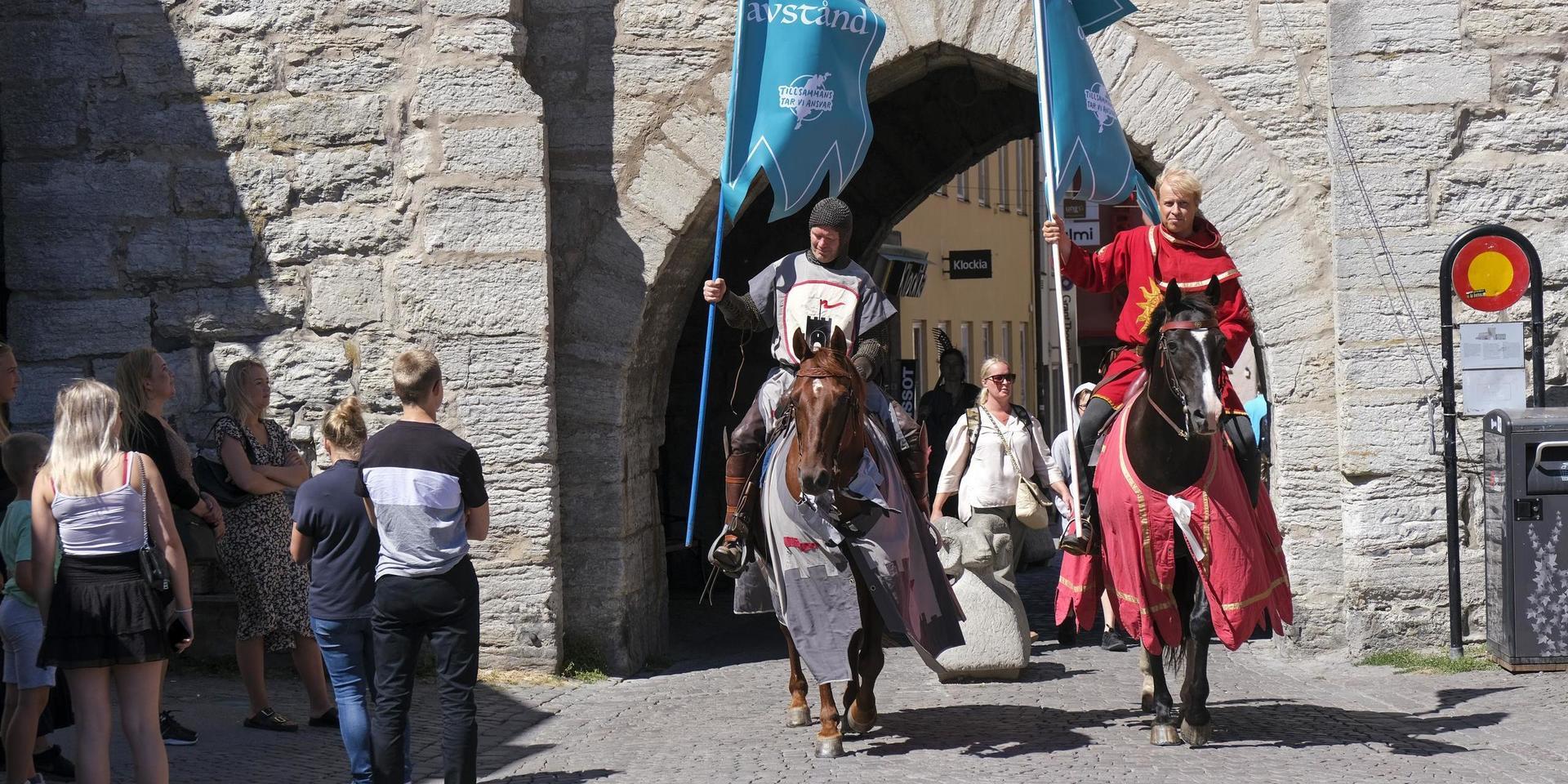 Torneamentums covidriddare ska påminna om att hålla avstånd under högskommarveckorna på Gotland. Här syns Thomas Lindgren på hästen Soprano och Anders Månsson på hästen Sara.