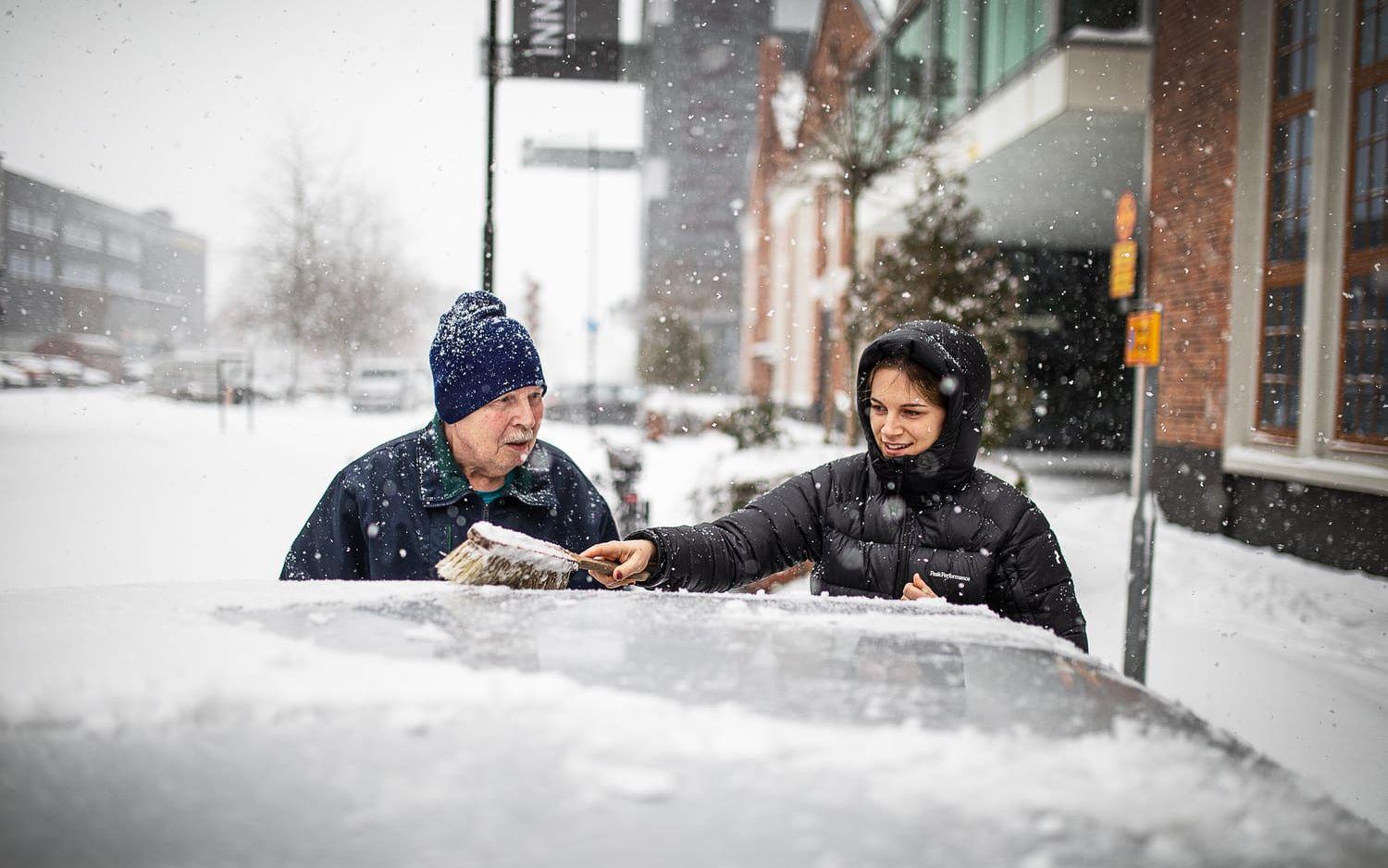 Leif Haglund får hjälp av Sofie Andersson att borsta bort snön från bilen. 