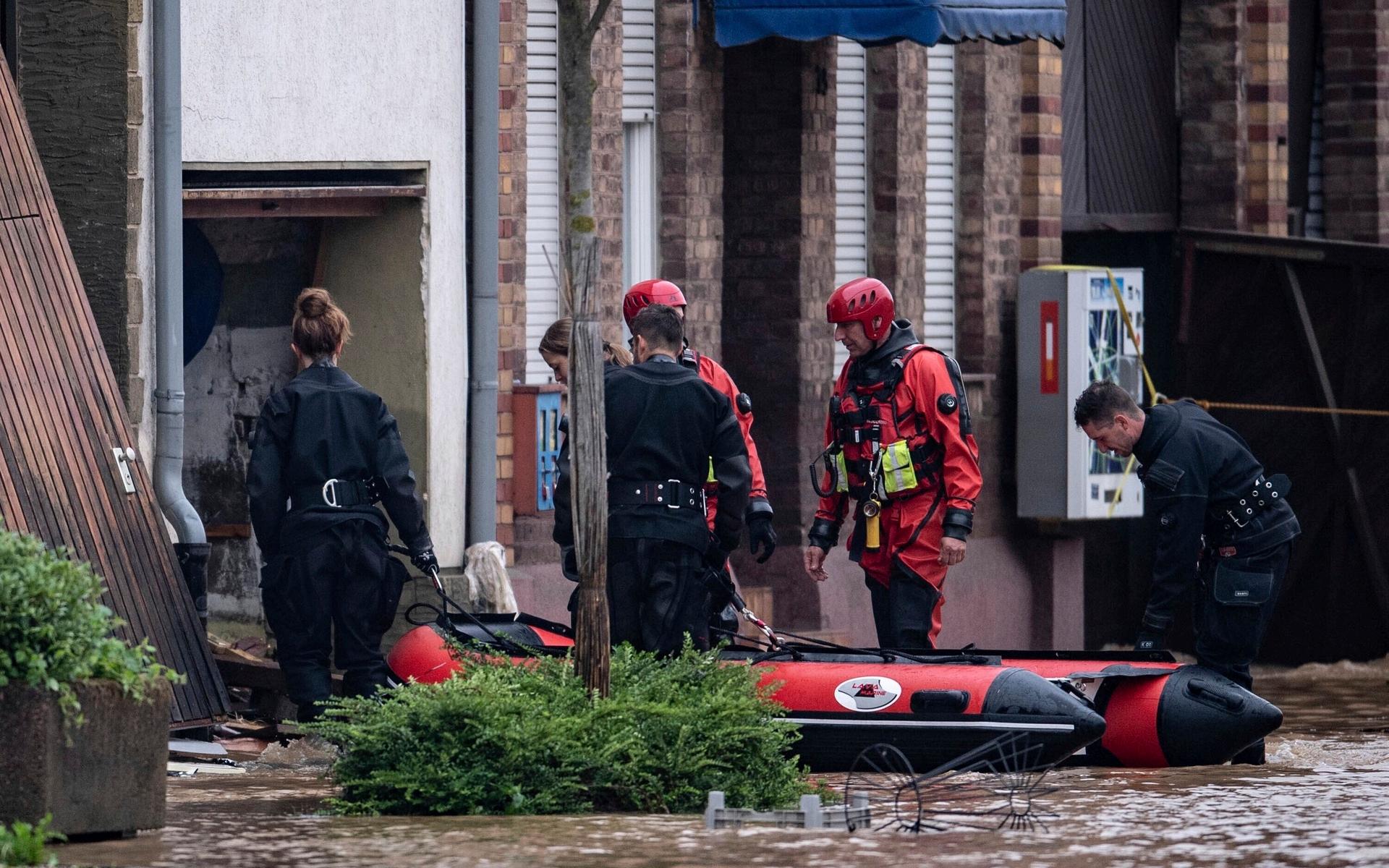Polisdykare går in i en översvämmad gård med en uppblåsbar båt i Erfstadt i Tyskland.