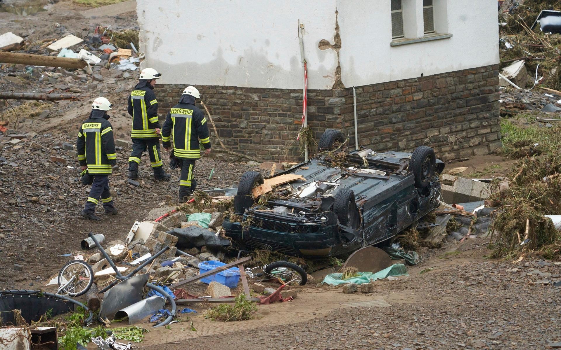 Brandmän vandrar förbi en förstörd bil i Schuld, Tyskland.