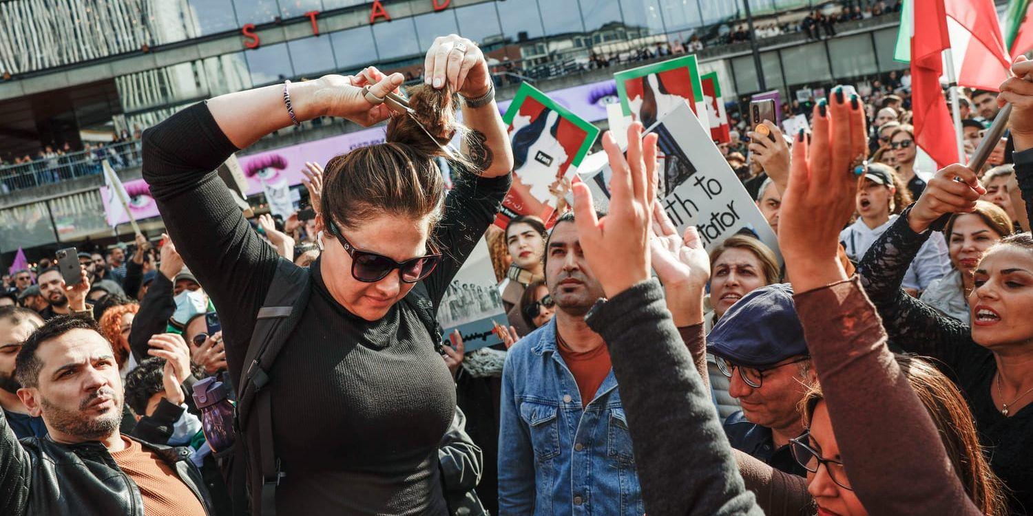 Azita Eriksson klipper av sitt hår under en demonstration i Stockholm till stöd för protesterna i Iran.