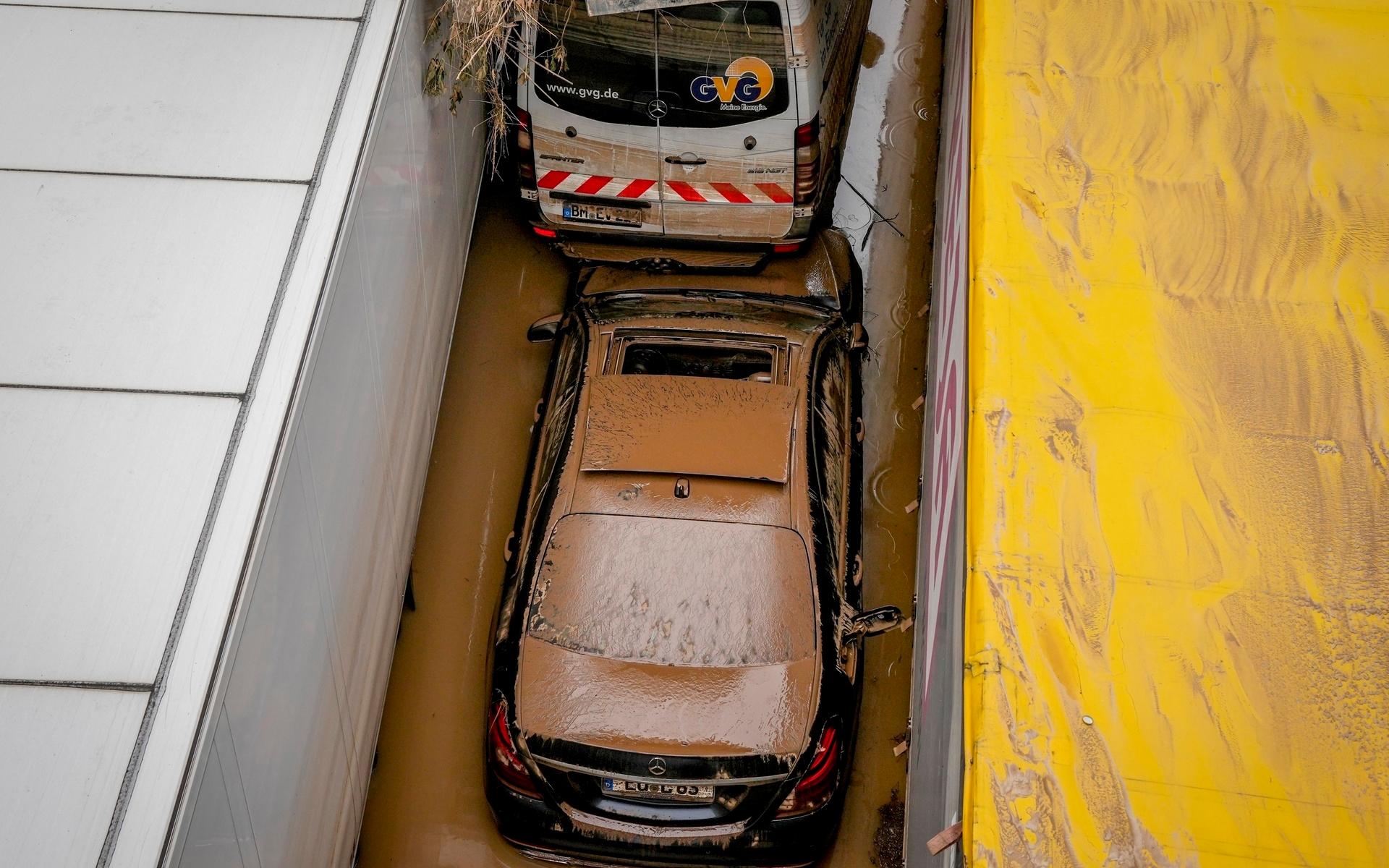 En bil fastnade mellan lastbilar på en översvämmad väg i Erftstadt.