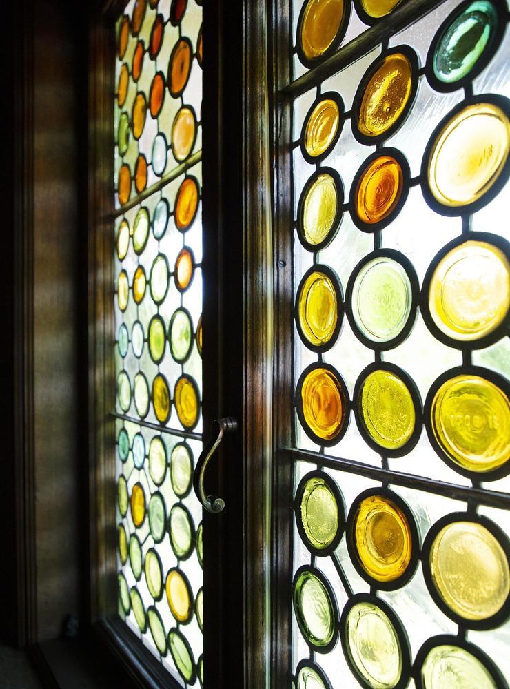 Vid entrédörren finns ett blyinfattat fönster där buteljbottnar i olika färger  använts som glas.