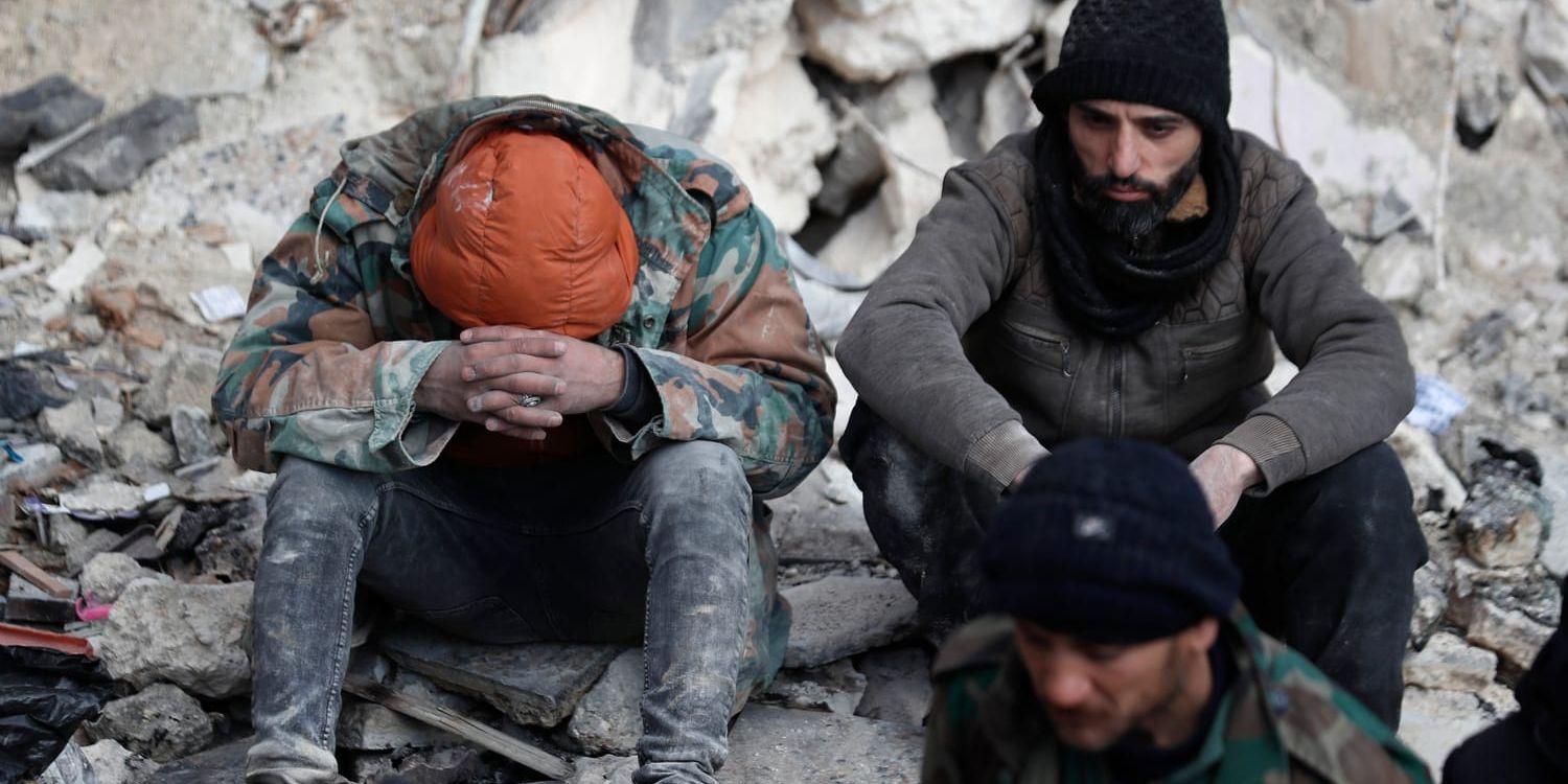 Två män pausar under räddningsarbetet i syriska Aleppo. Det krigshärjade Syrien har drabbats hårt av jordbävningskatastrofen.