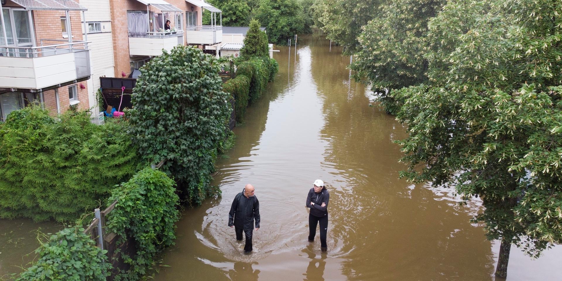 Två personer vadar genom översvämning vid ett bostadsområde vid Södra Kungsvägen i Gävle.
