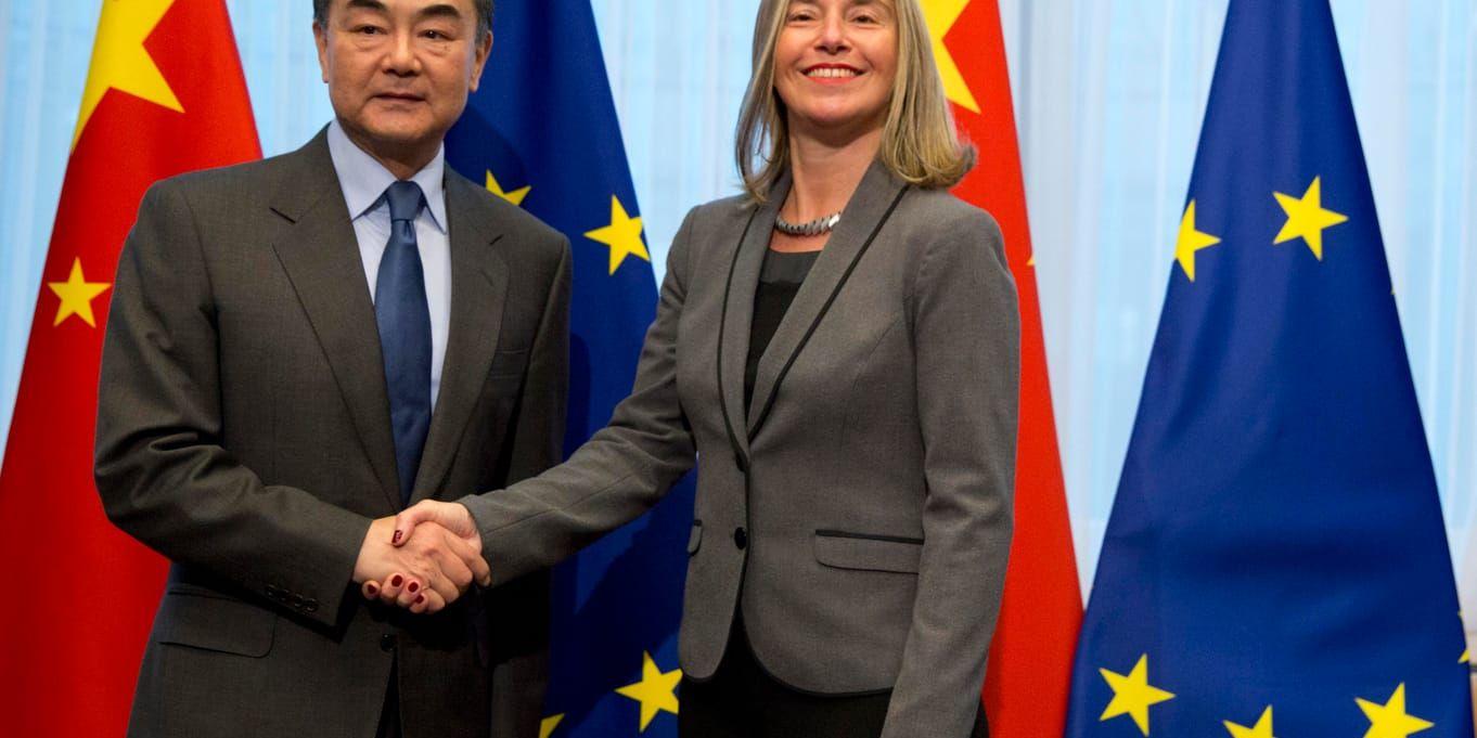 Kinas utrikesminister Wang Yi skakar hand med EU:s utrikeschef Federica Mogherini i Bryssel.