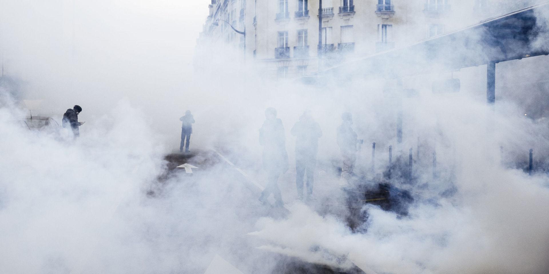 Demonstranter står i ett hav av tårgas i Paris. 