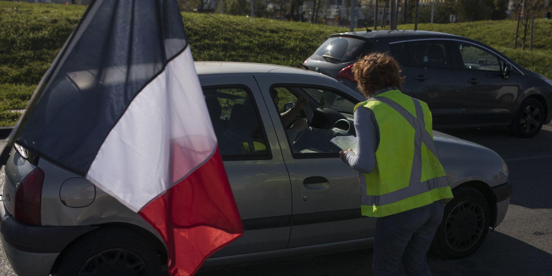 En kvinna delar ut flygblad till en bil som passerar en demonstration i Marseille.