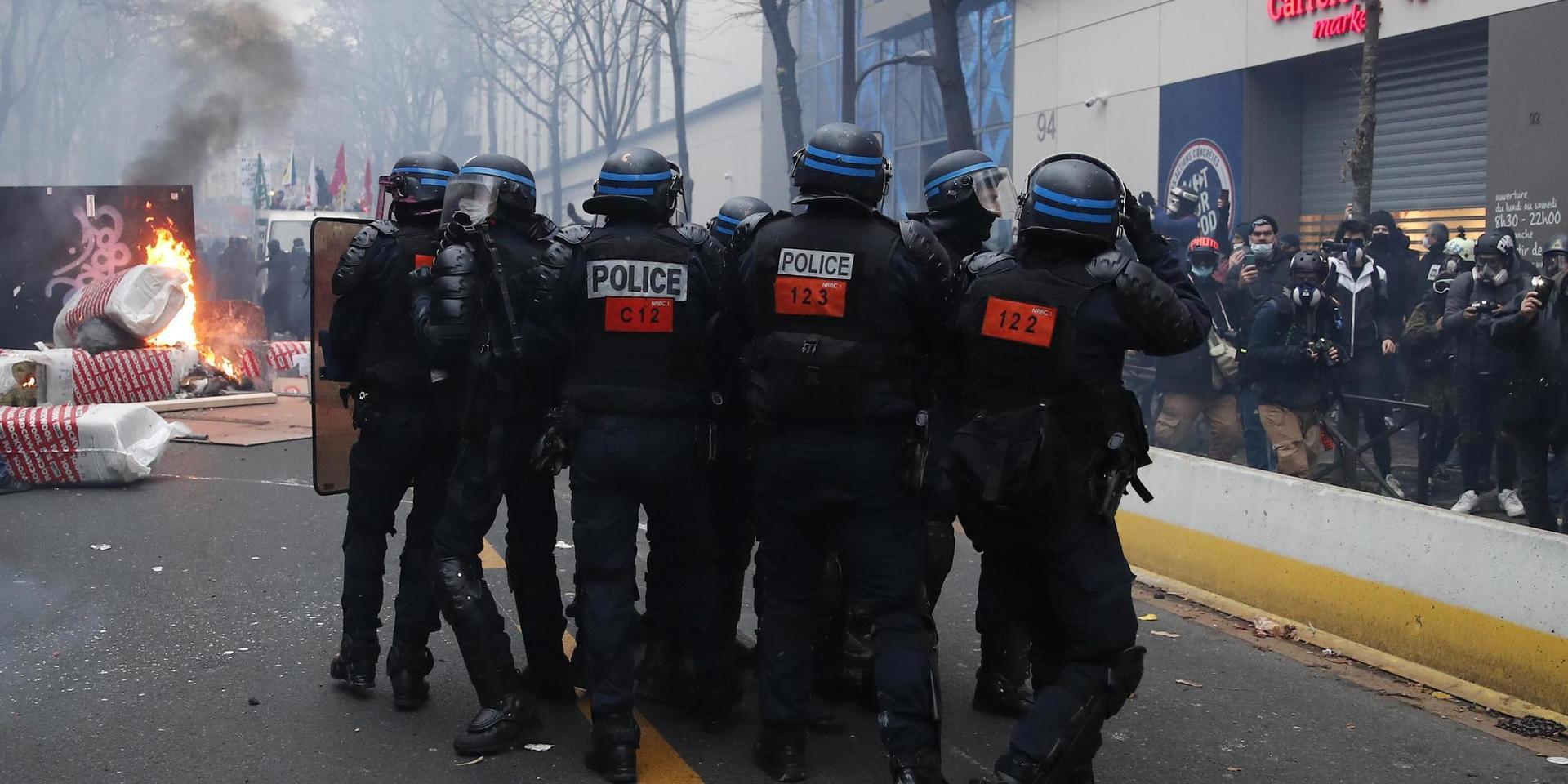 Kravallpolis närmar sig en brinnande barrikand under lördagens våldsamma protester i Paris.