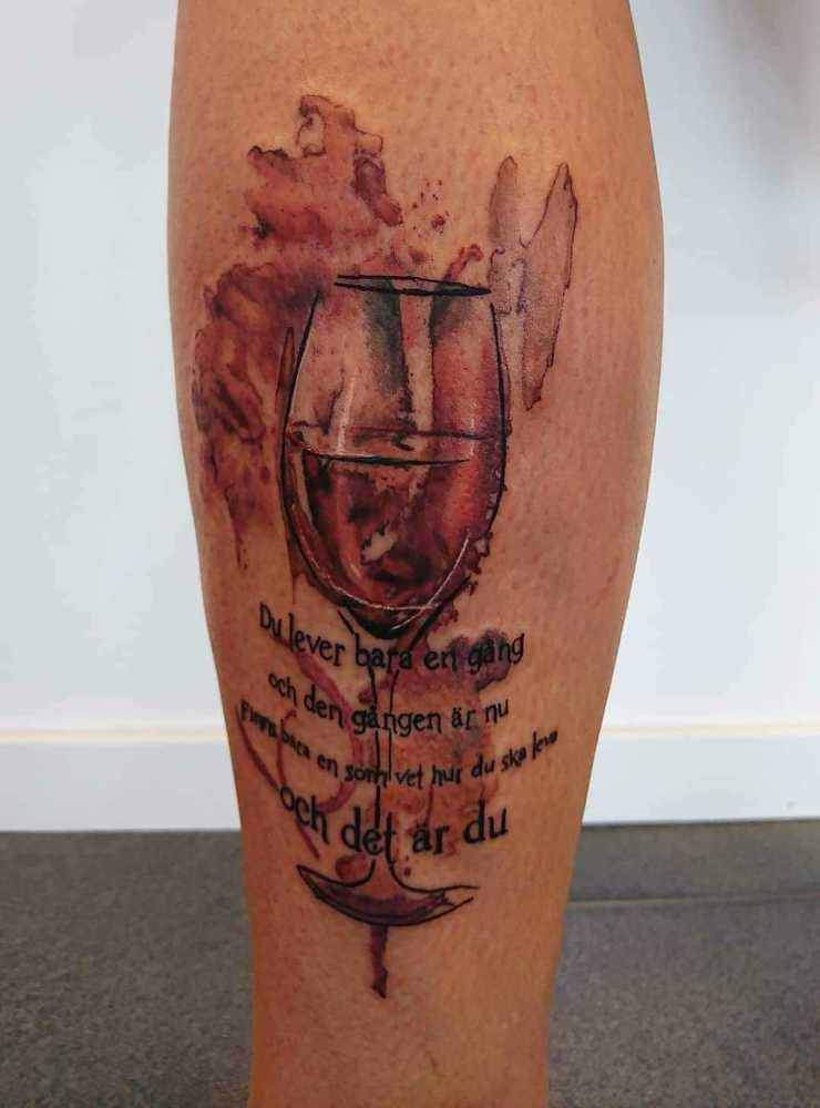 Linda Haglund har tatuerat in ett vinglas och en text.