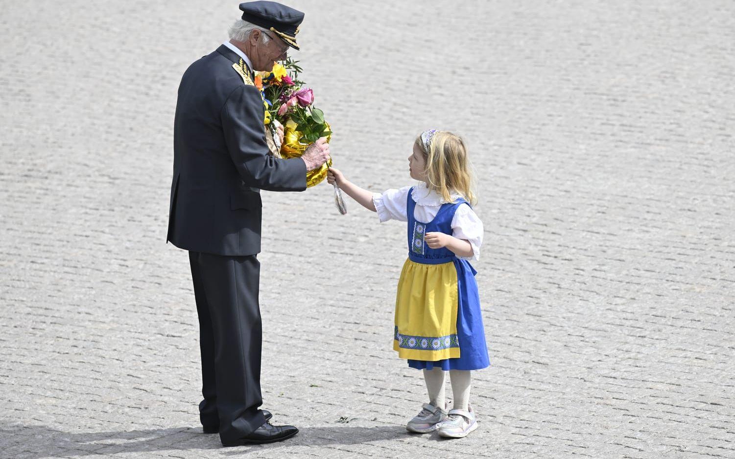 Fyraåriga Sally Leijonmarck överlämnar en blomma till kung Carl Gustaf vid firandet på yttre borggården vid Stockholms slott.
