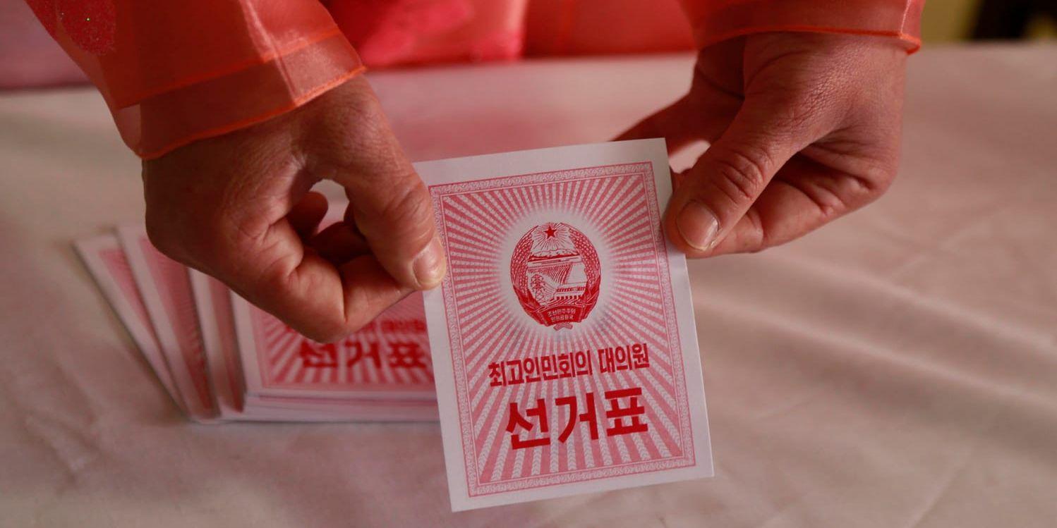 En valarbetare visar en valsedel i en röstlokal i huvudstaden Pyongyang i Nordkorea.