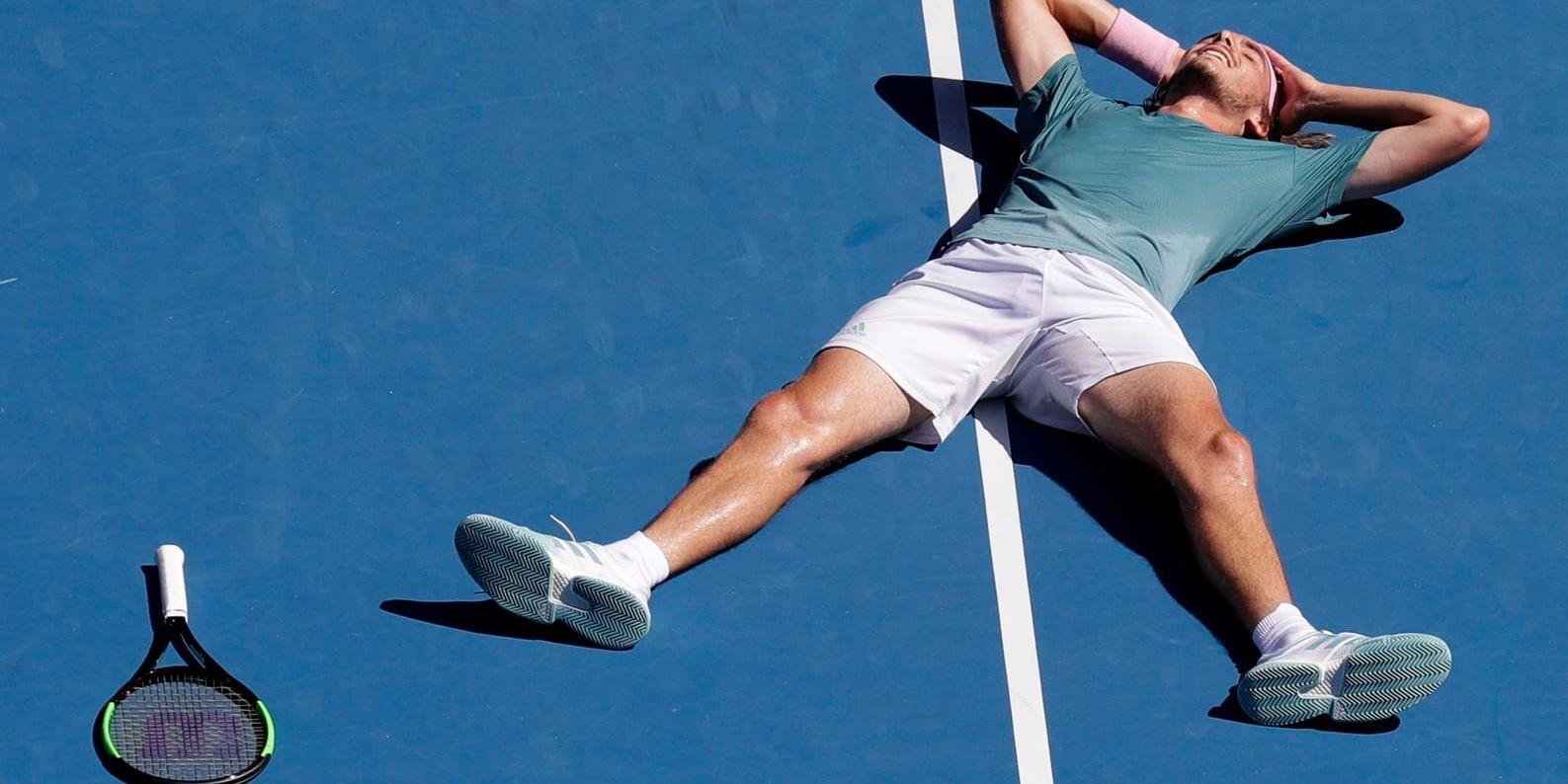 Stefanos Tsitsipas pustar ut och firar liggande efter att ha säkrat semifinalplatsen i Australian Open.