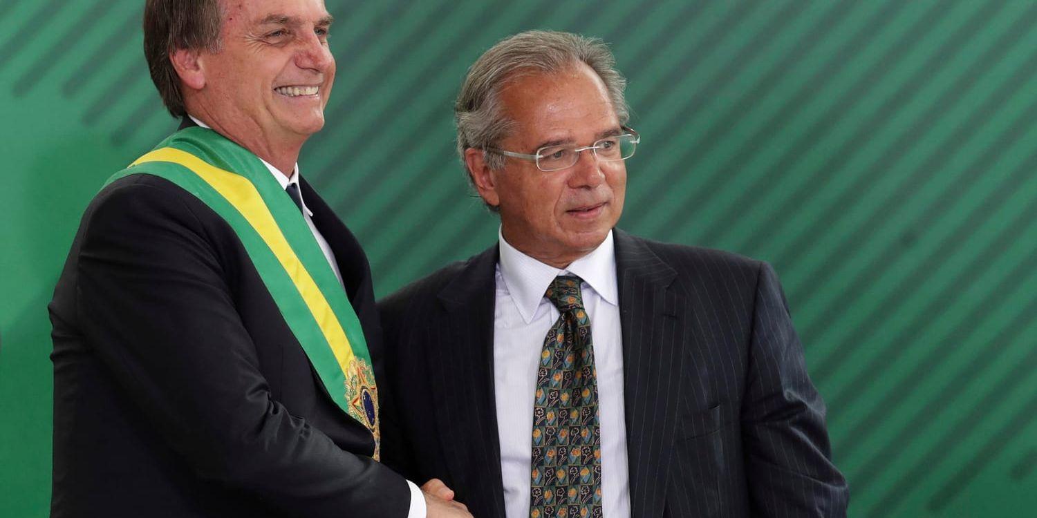 Brasiliens president skakar hand med sin finansminister Paulo Guedes under en ceremoni i huvudstaden Brasília den 1 januari.