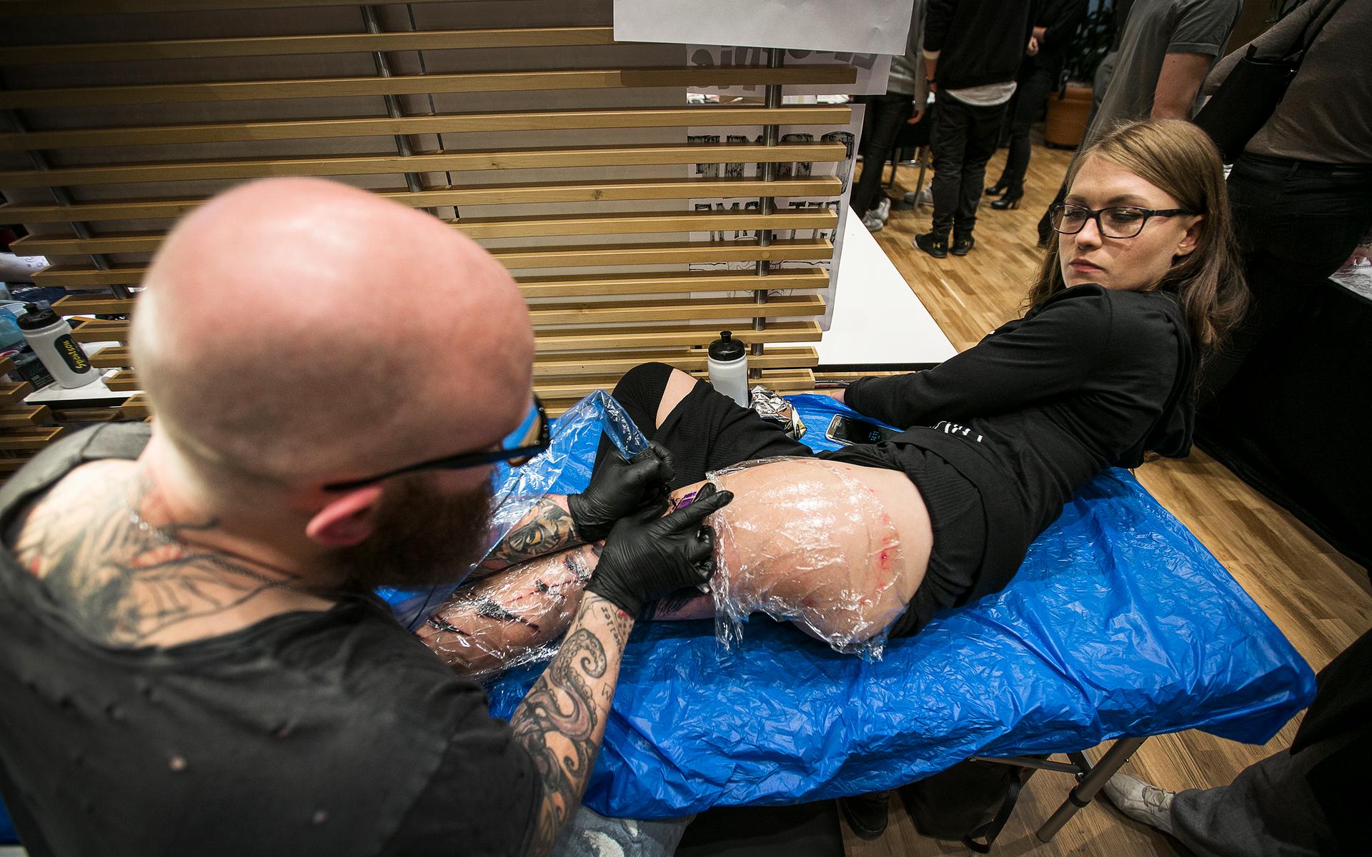 Angelica Fogelström får en läcker tatuering på benet. Jacob Pedersen arbetar för fullt.