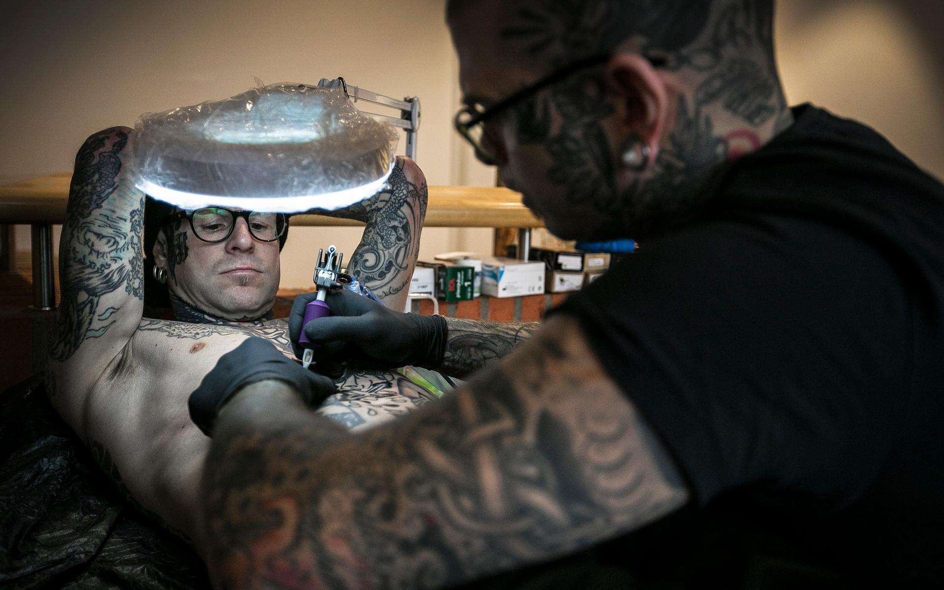 Peter Bark får en tatuering på magen. Mattias Andersson håller i arbetet.