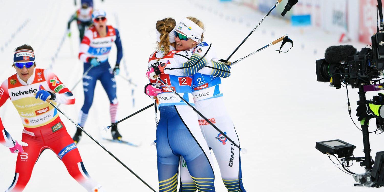 Sveriges Stina Nilsson och Maja Dahlqvist kramar om varandra efter segern i damernas final i sprintstafetten i skid-VM i Seefeld.