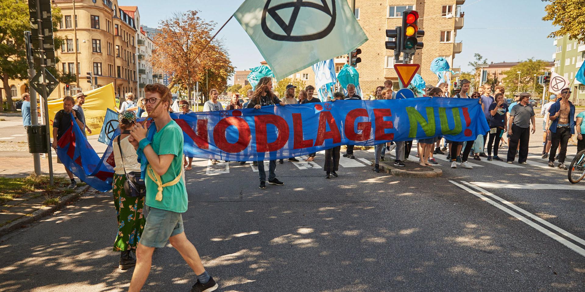 'Klimatnödläge' står det på en banderoll som demonstranter från rörelsen Extinction Rebellion håller upp när de spärrade av en korsning längs Östra Rönneholmsvägen i Malmö i augusti i år. 