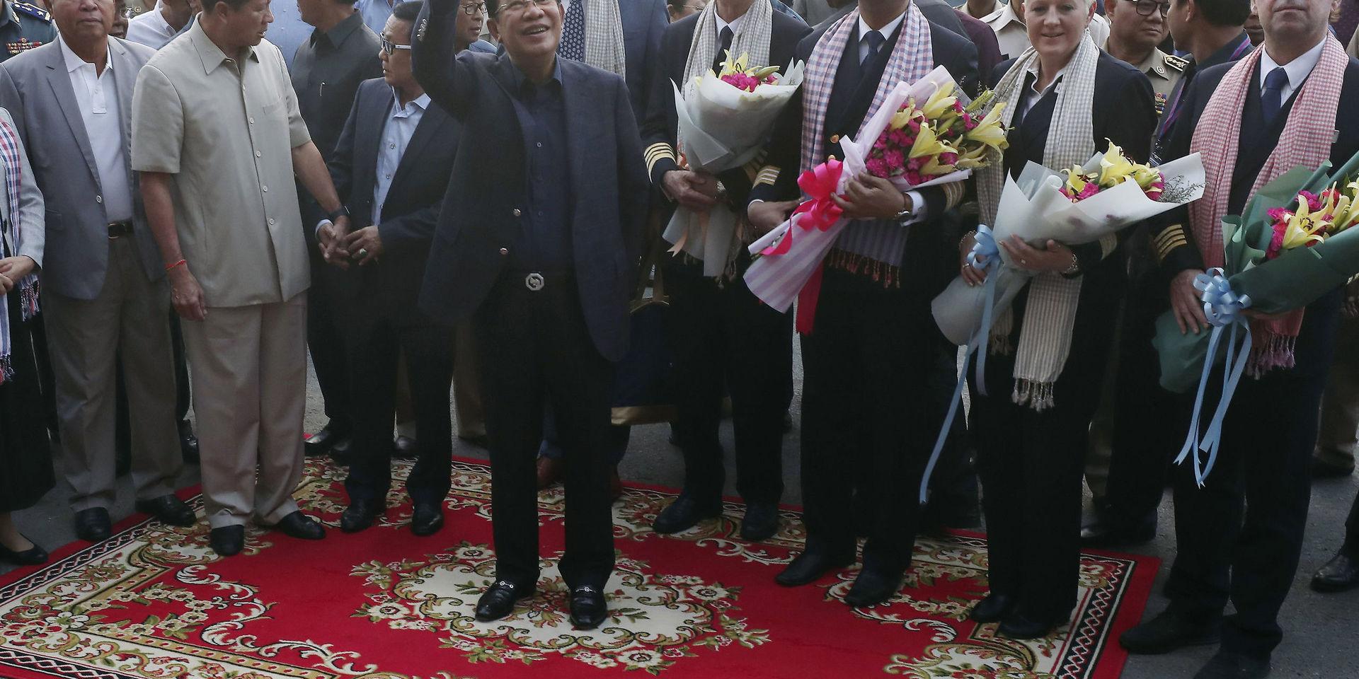 Passagerare välkomnades med blommor av Kambodjas premiärminister Hun Sen (vinkande i mitten) i Sihanoukville. 