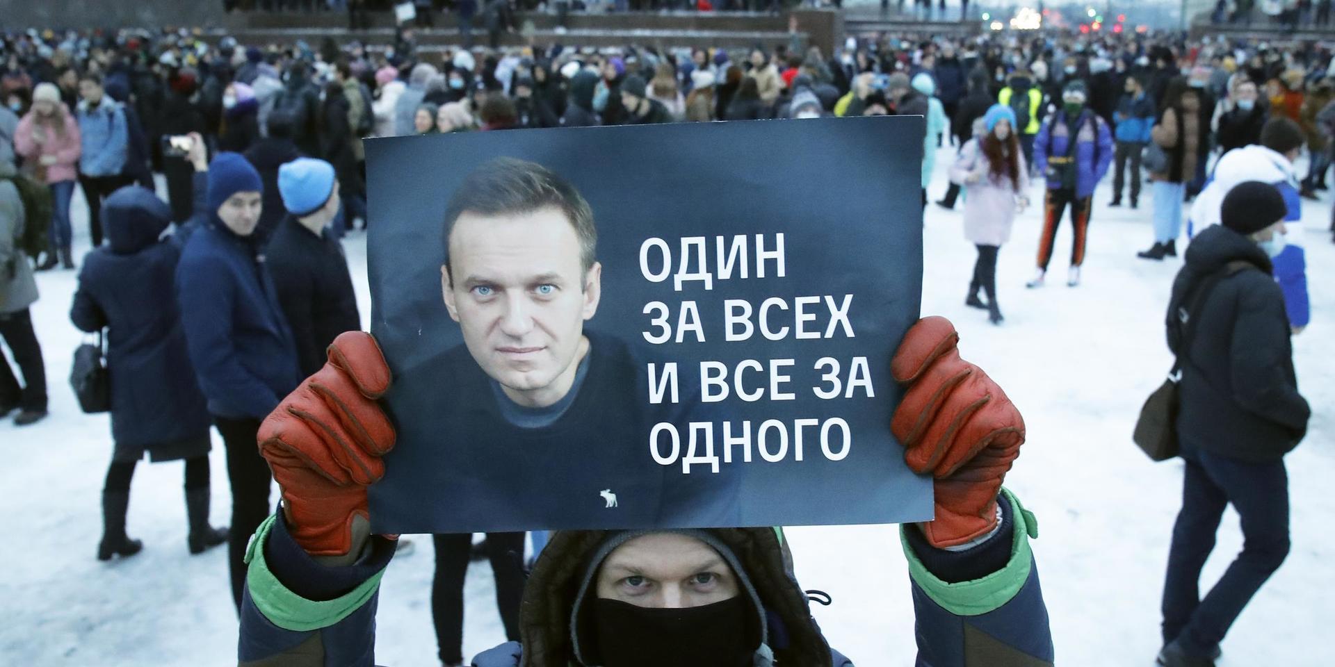 En demonstrant med ett plakat med en bild på den fänglsade oppositionsledaren Aleksej Navalnyj och texten 'En för alla, alla för en' under protester i S:t Petersburg i lördags.