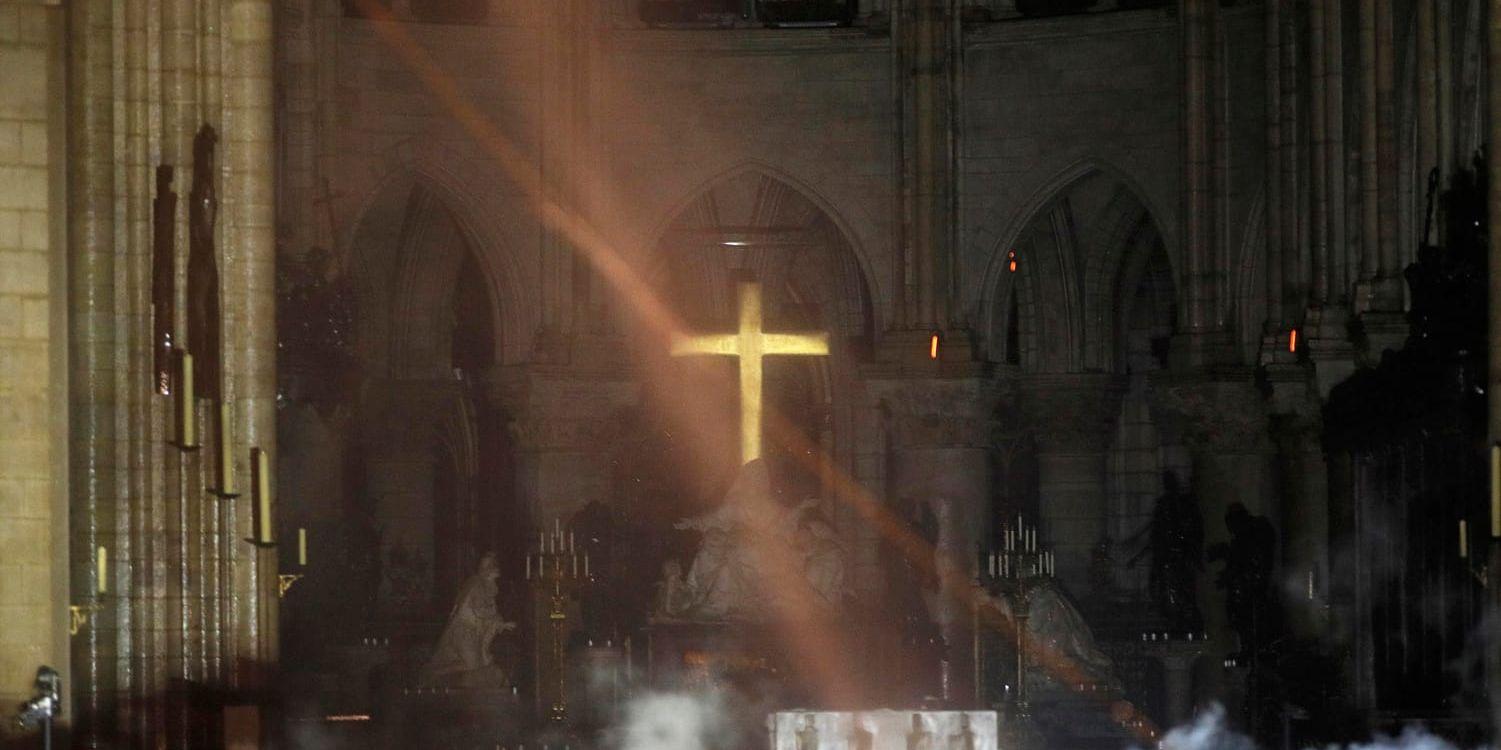 En av de första bilderna inifrån katedralen Notre-Dame efter branden. Rök syns framför altaret.