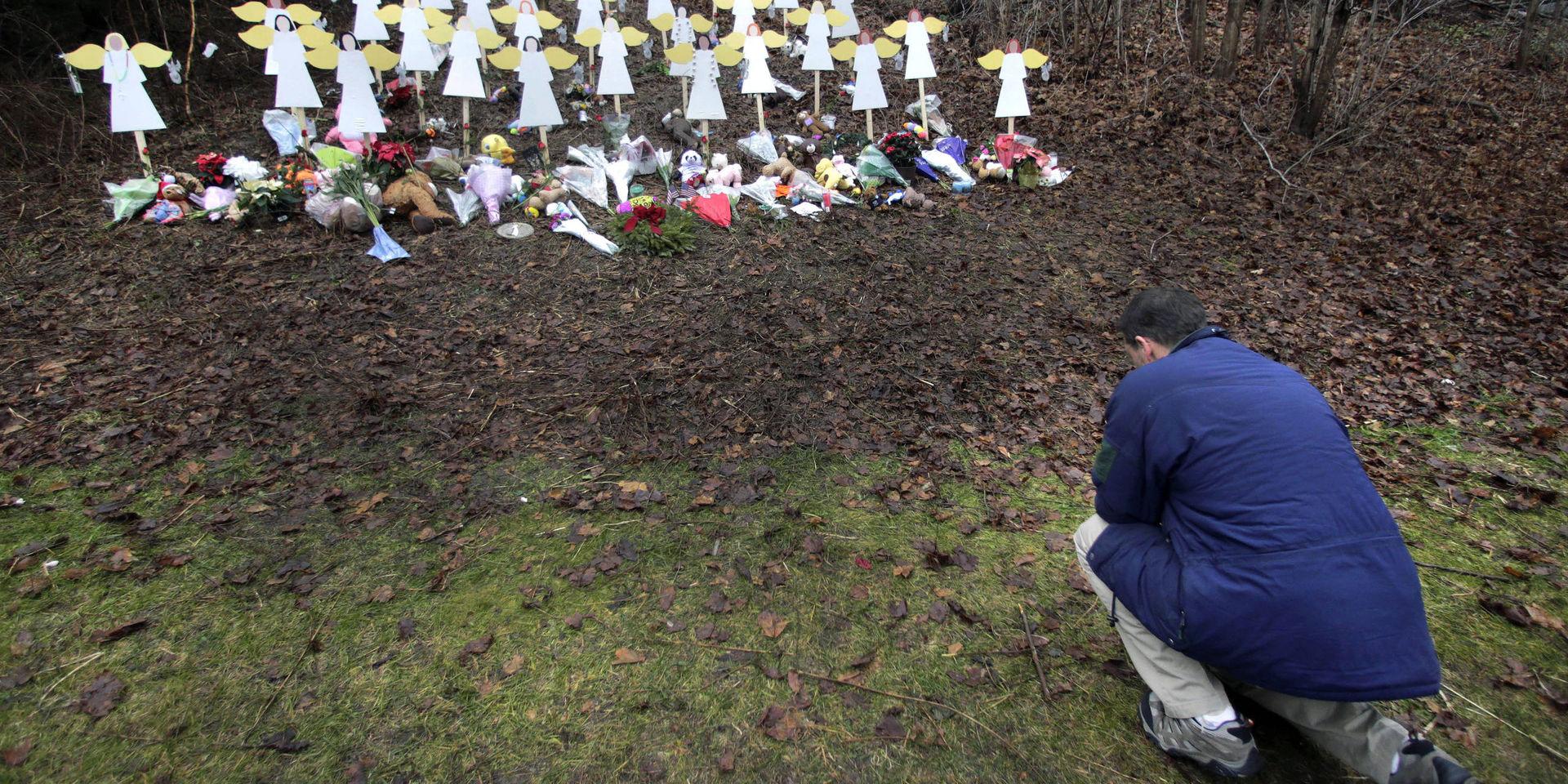 En man hedrar offren vid den minnesplats som utformades efter Sandy Hook-massakern år 2012 då 20 barn och sex lärare mördades av en ensam gärningsman Arkivbild 