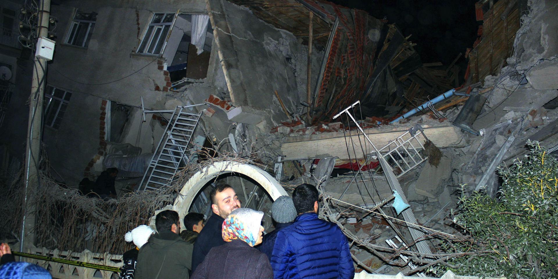 Människor framför en byggnad som rasat samman i staden Elazig i östra Turkiet. Minst fyra människor dog i en kraftig jordbävning.