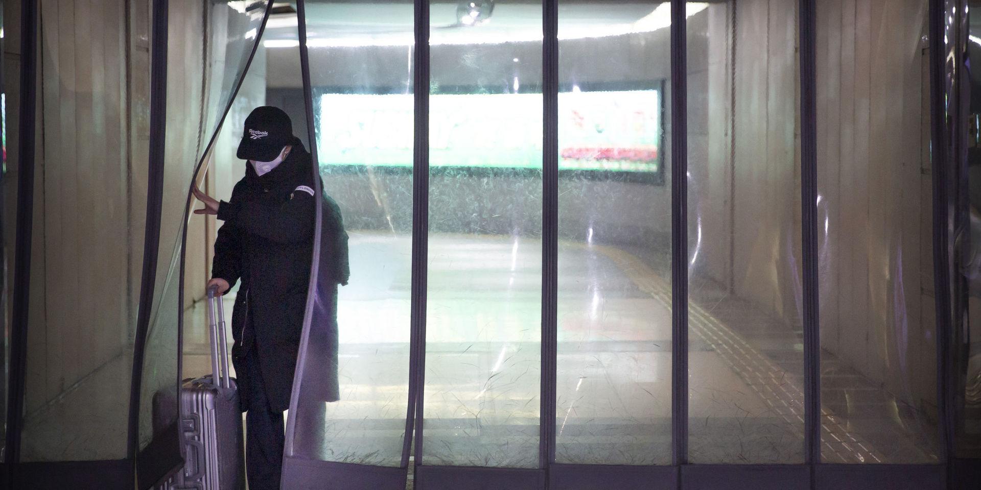 En person med ansiktsmask vid en tunnelbanestation i Kinas huvudstad Peking på söndagen. 