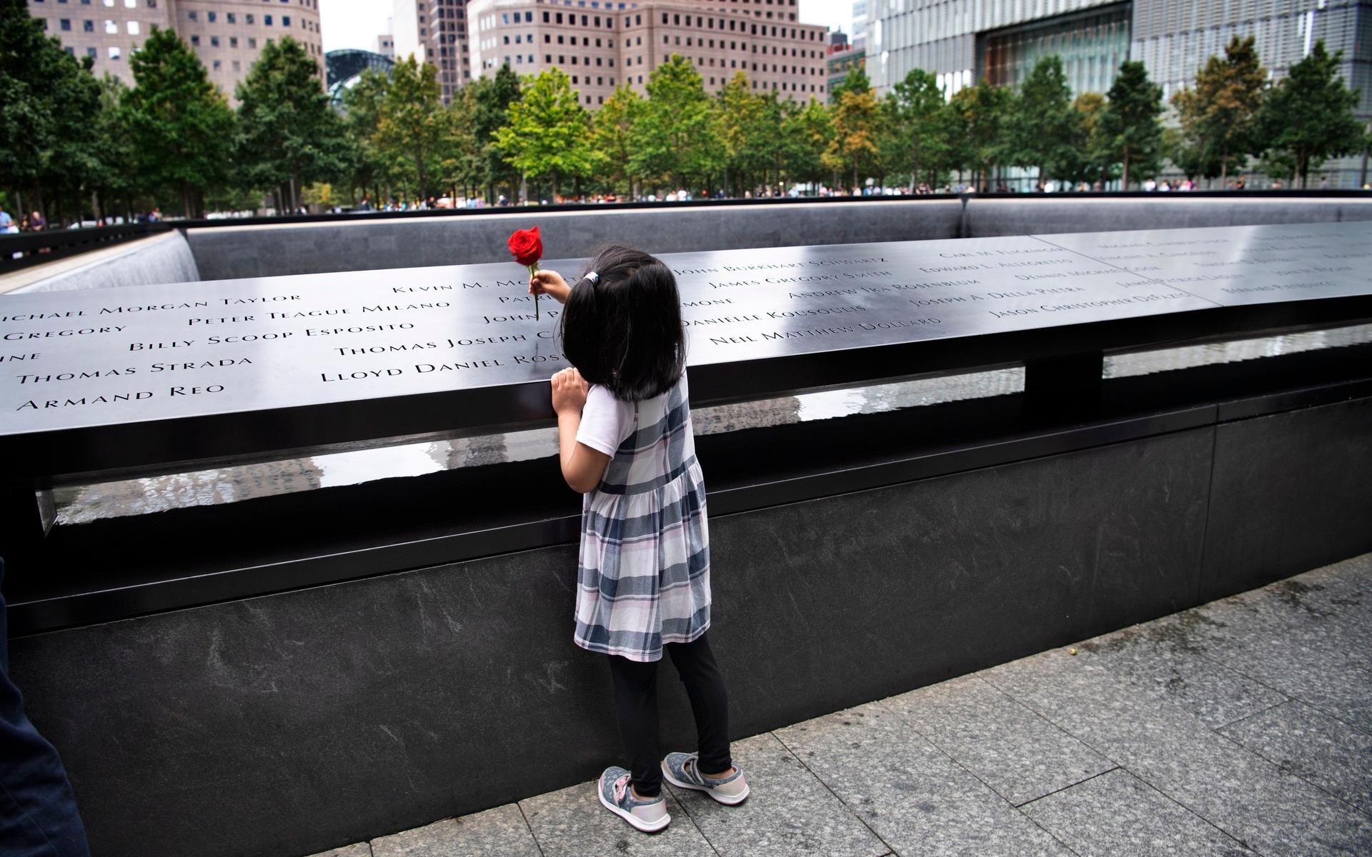 En flicka sätter en ros bland namnen på offren i attackerna.