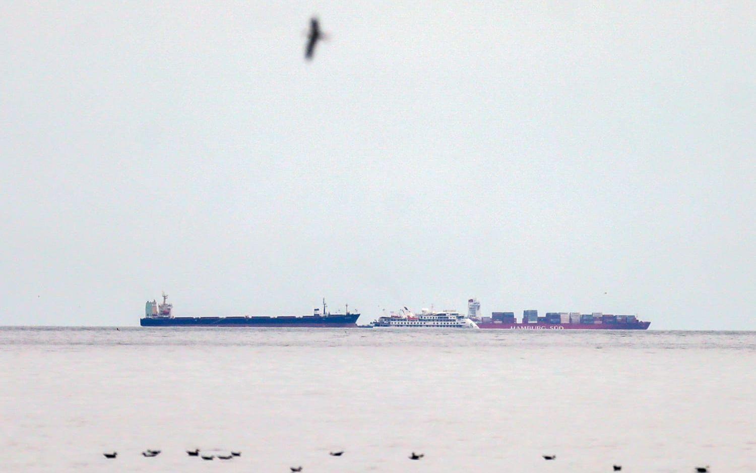 Det virusdrabbade kryssningsfartyget Greg Mortimer omgivet av två lastfartyg utanför hamnen i Montevideo.