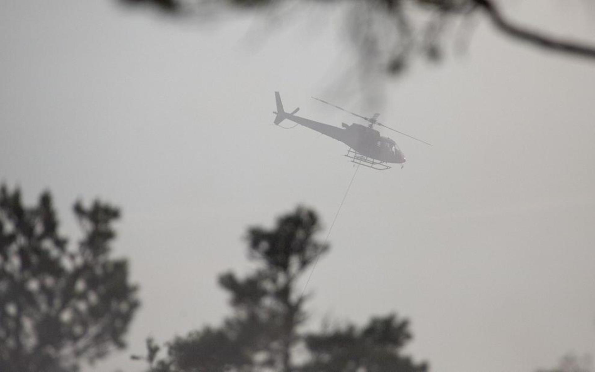 En helikopter har kallats in för att vattenbomba elden från luften. Bild: Linus Olsson