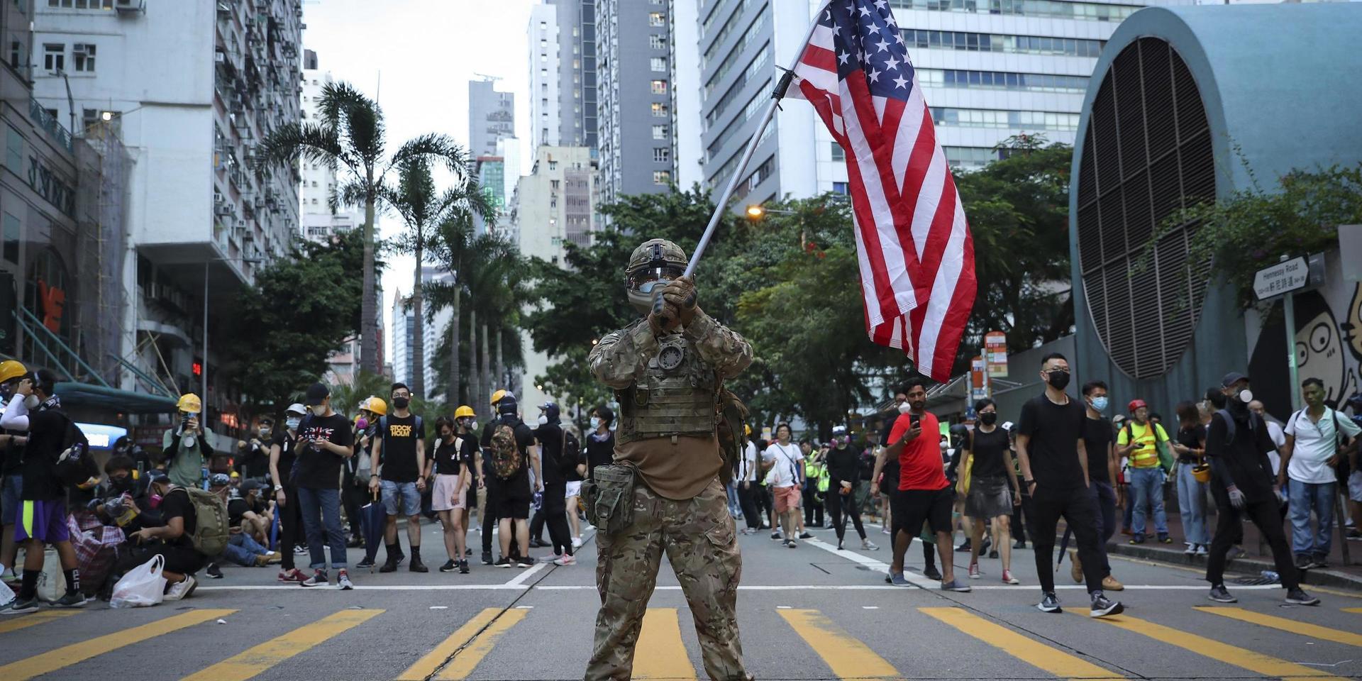En demonstrant utklädd till militär håller en amerikansk flagga under demokratiprotester i Hongkong i augusti 2019. 
